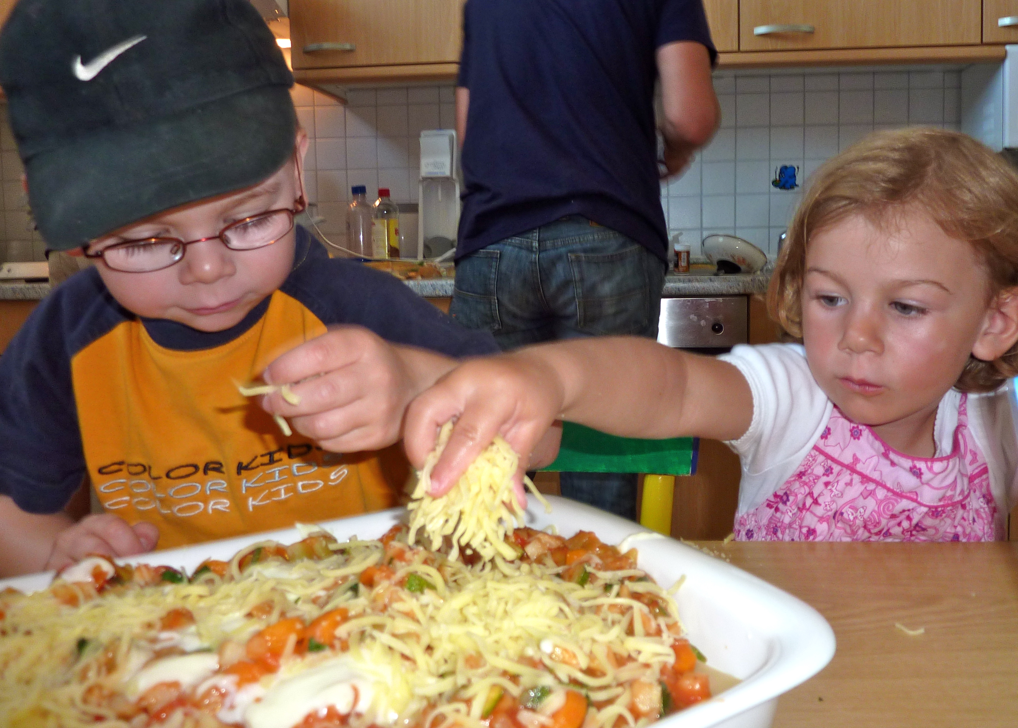 Norderney - Mädchen streut Käse über Gemüselasagne