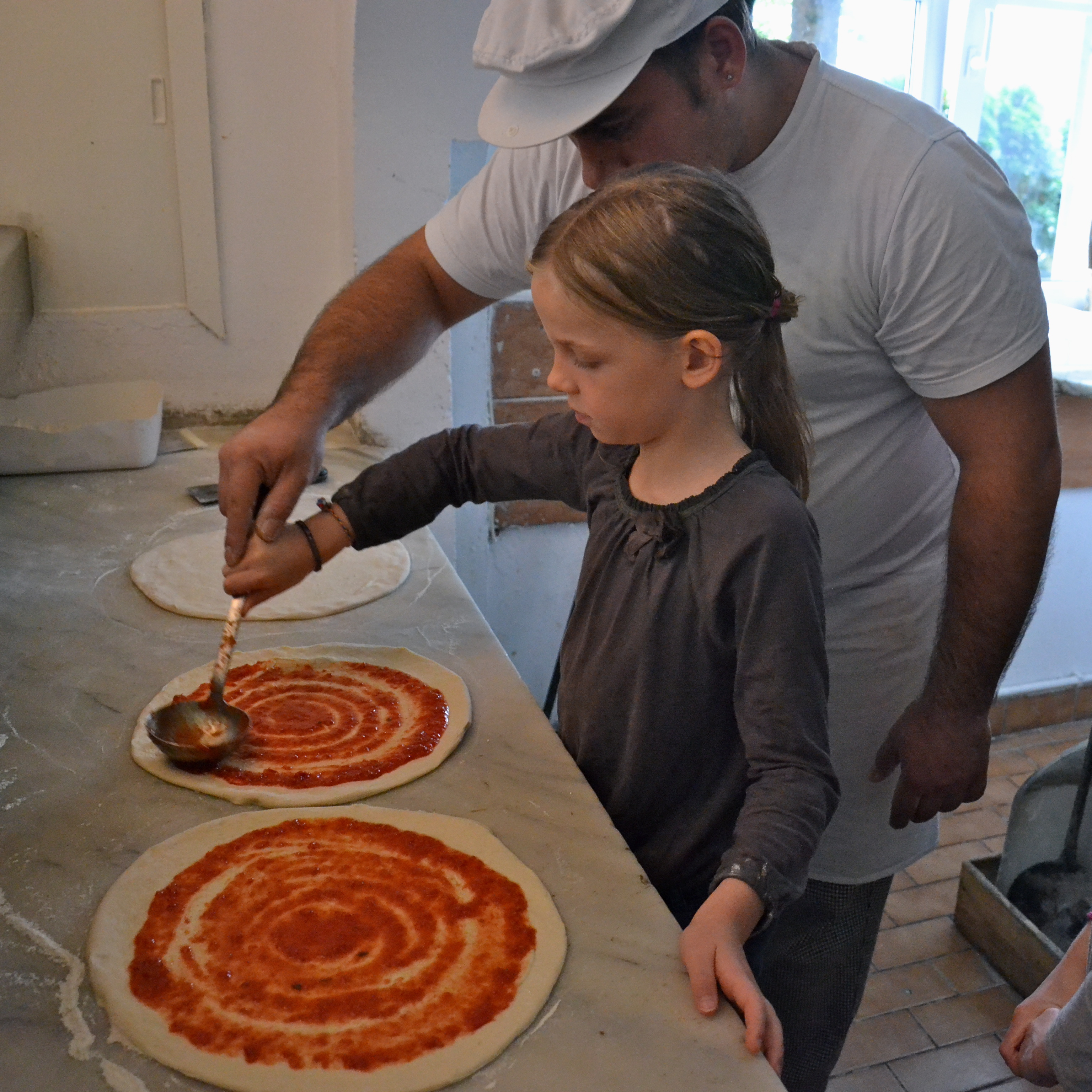 Kinderpizza - Anna bestreicht ihre Pizza mit Tomatensauce