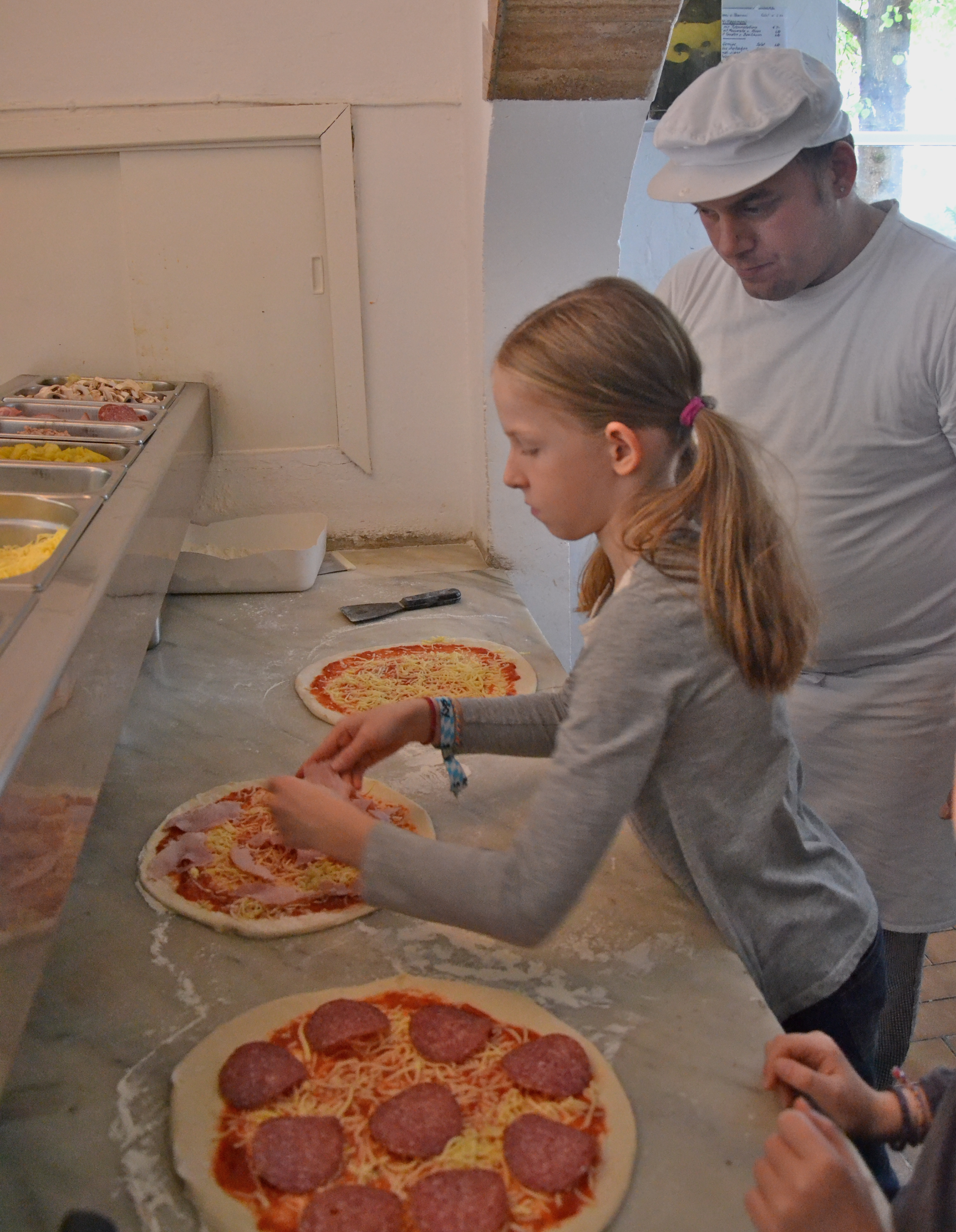 Kinderpizza - Marie legt gekochten Schinken auf ihre Pizza