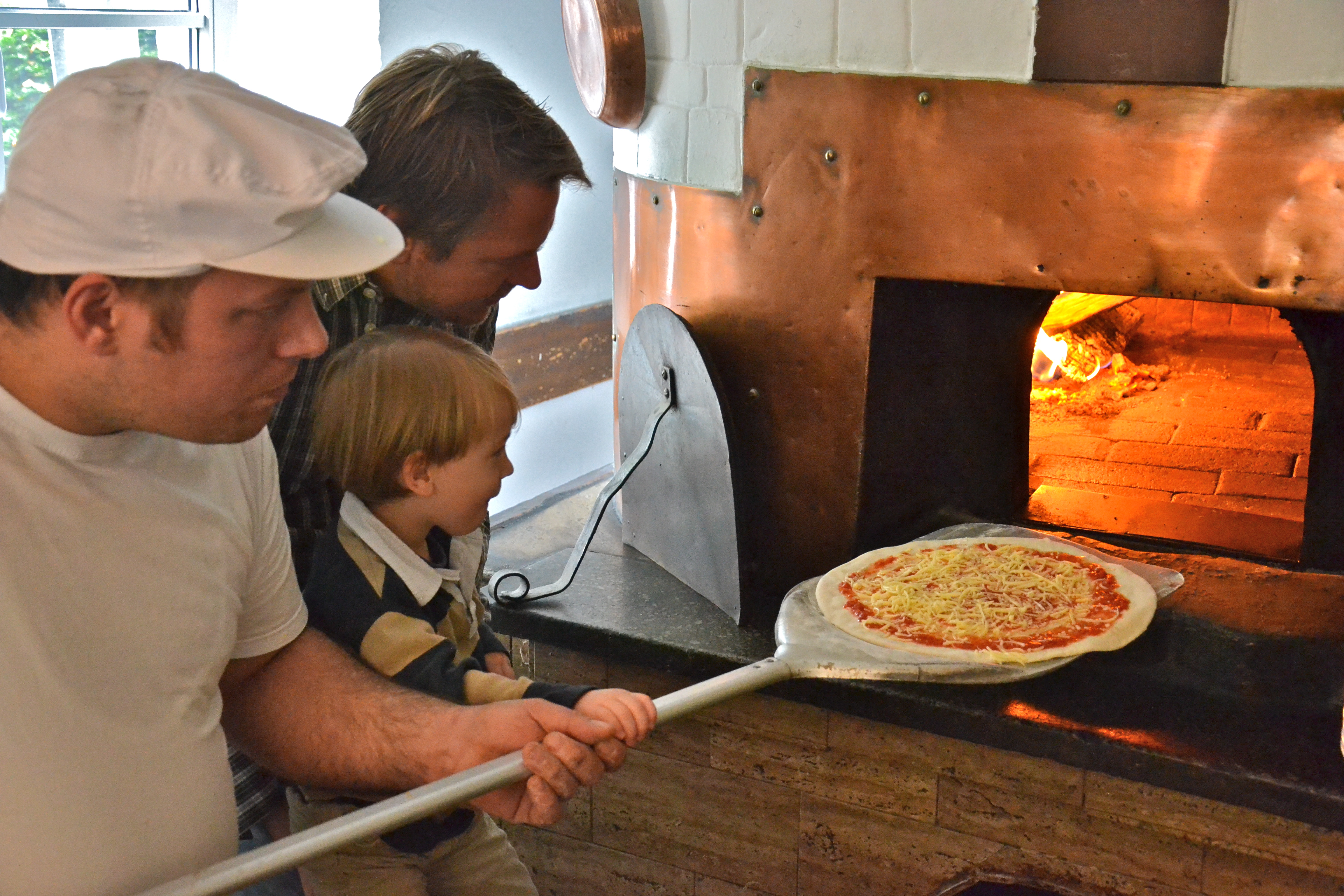Kinderpizza - Peter schiebt seine Pizza in den Holzofen